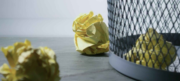 focus photo of yellow paper near trash can